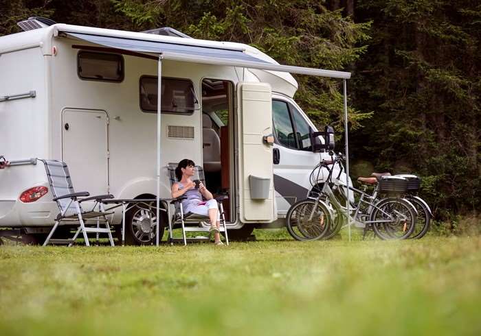 autocamper-med-kvinde-foran-og-cykler